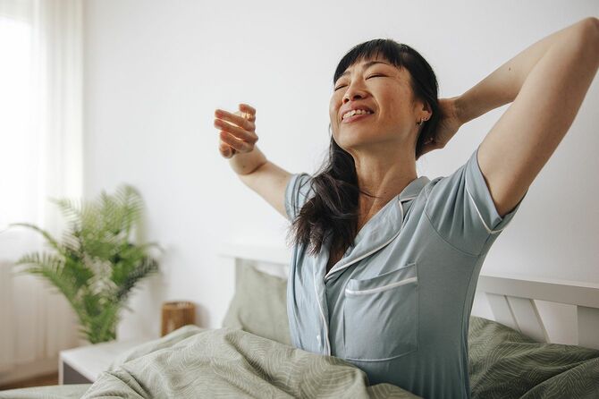 ベッドの上で伸びをする女性