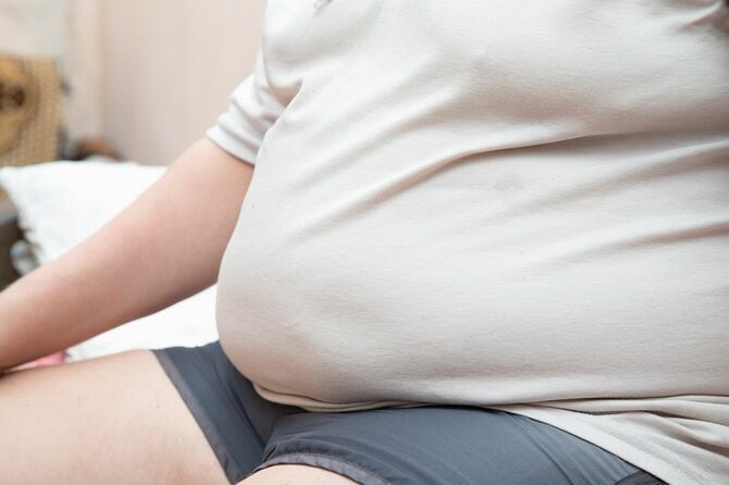 大きな腹を持つ男がベッドに座っています