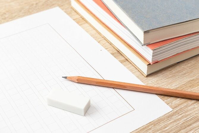 積まれた本と鉛筆、消しゴム、原稿用紙