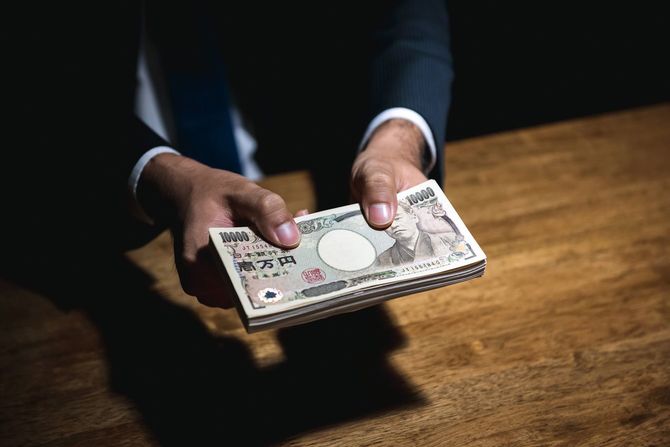 暗い部屋で札束を差し出す実業家