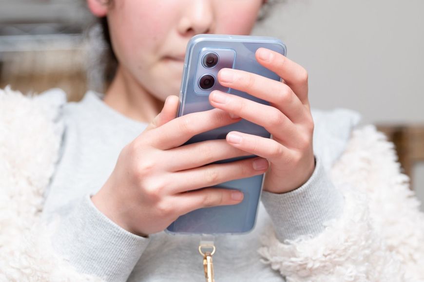 家でスマホを見ている女の子