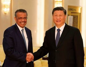 WHO（世界保健機関）のテドロス事務局長（左）と握手する中国の習近平国家主席。