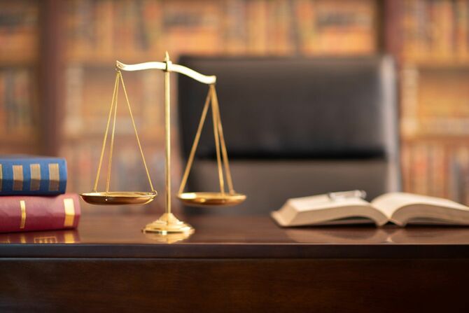 弁護士事務所の机の上の正義のスケールと法律書