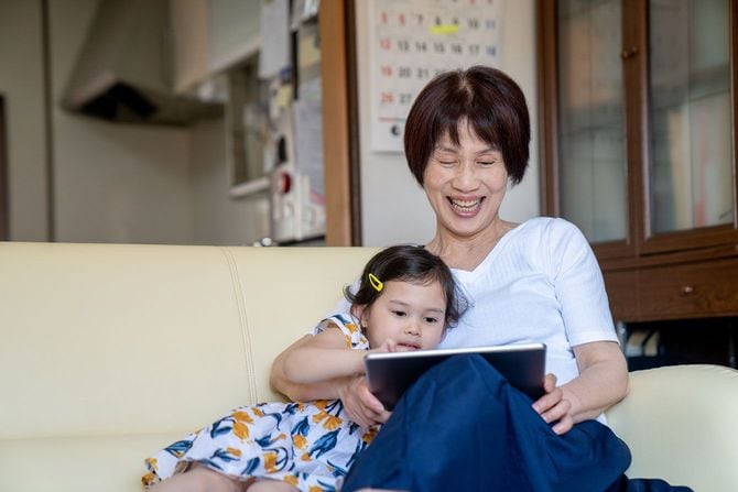 笑顔で一緒にタブレットを見ている祖母と孫