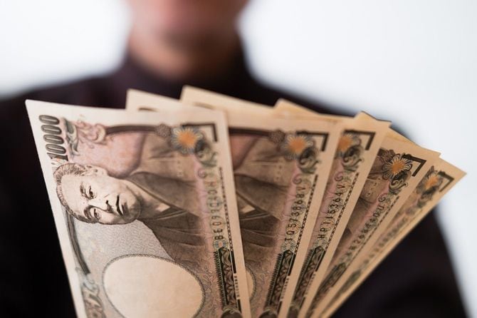 1万円札の束を持つ男性