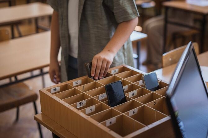 自分のスマートフォンを教室の収納箱に入れる学校の生徒