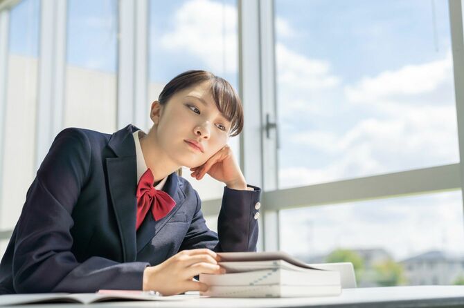 教室の窓際で勉強する高校生
