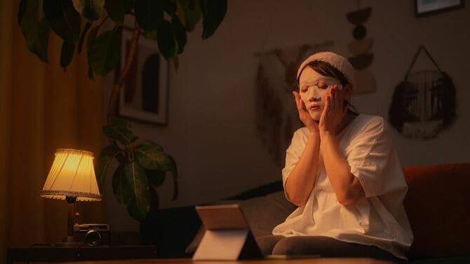 夜のリビングルームで肌パックを使ってスキンケアをする女性