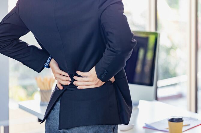 オフィスで腰痛に苦しむビジネスマン