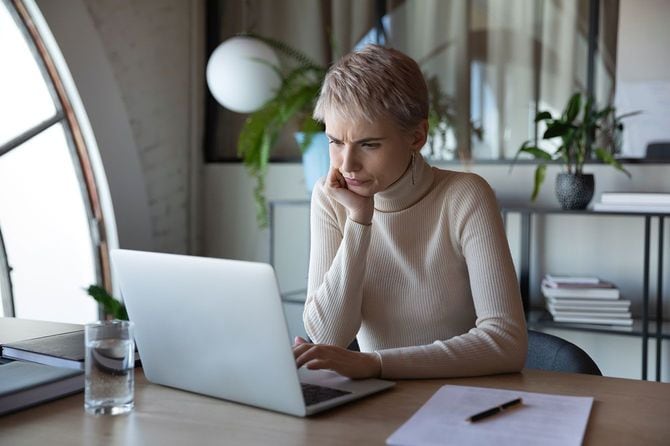 パソコンの画面を見て顔をしかめる女性