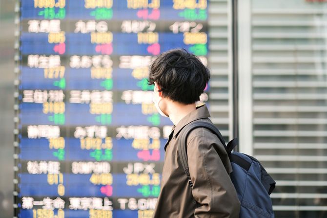 株式市場の電光掲示板を見るビジネスマン