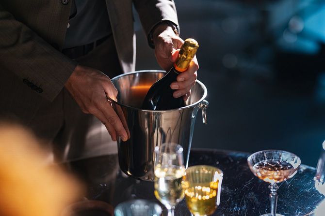 ボトルクーラーに入れたシャンパンを持つ人