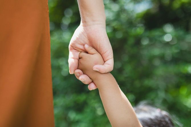 公園で子供の手を握る母親の手