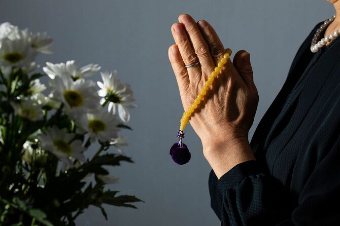 葬式で数珠を持ち手を合わせる女性