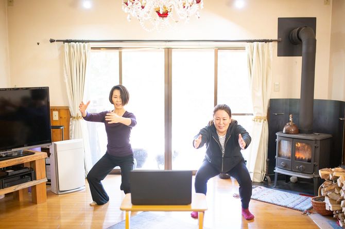 ラップトップを見ながら運動する親子