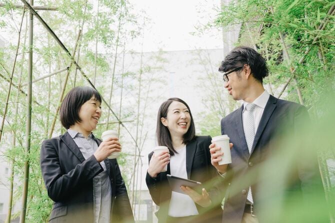 屋外で談笑する3人のビジネスパーソン