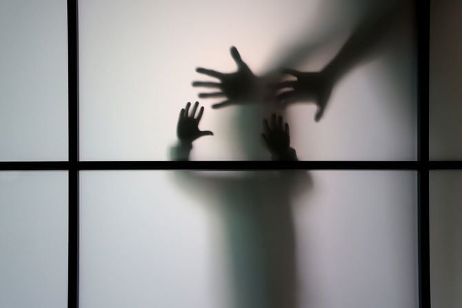 すりガラスの扉を開けようとしている園児と、それを阻止しようとしている親のシルエット