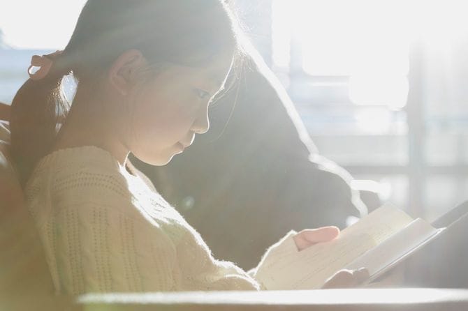 ソファーで本を読んでいる女の子