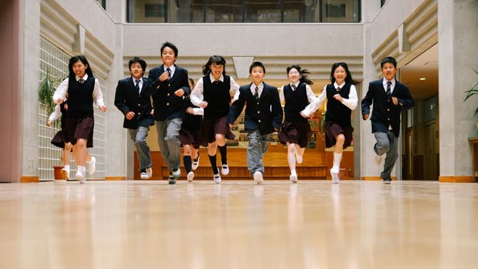 校内で制服を着た学生10人がこちらに走ってくる