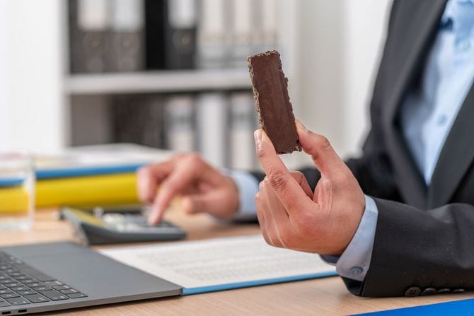 チョコレートスナックバーを食べるビジネスマン