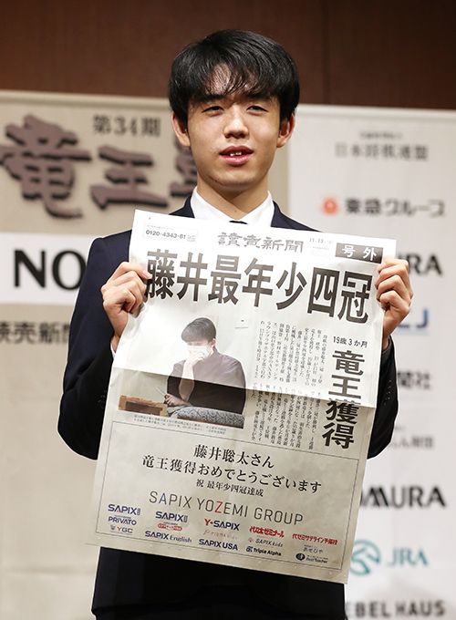 史上最年少四冠を達成し、新聞の号外を手に笑顔を見せる藤井聡太四冠＝2021年11月14日、山口県宇部市（写真＝時事通信フォト）