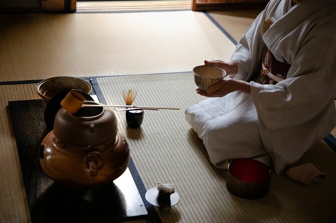 着物を着た日本人女性がひざまずいて茶道の物を用意している