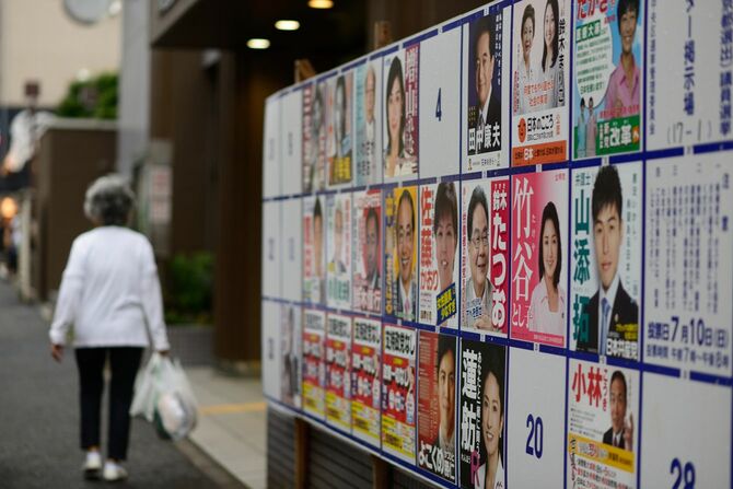 2016年の参議院選挙のポスター掲示板の前を通り過ぎるシニア女性