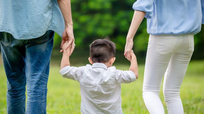 子どもと手をつなぎ、一緒に歩く両親
