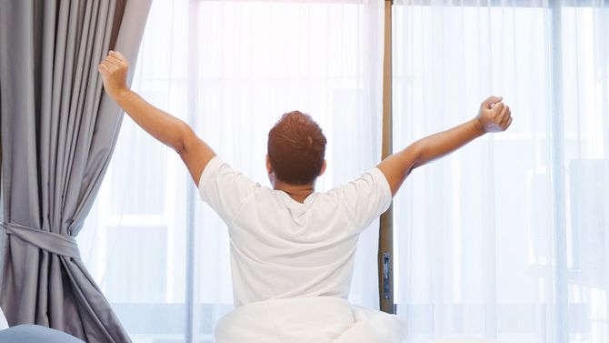 朝、寝起きの男性が体を伸ばしている