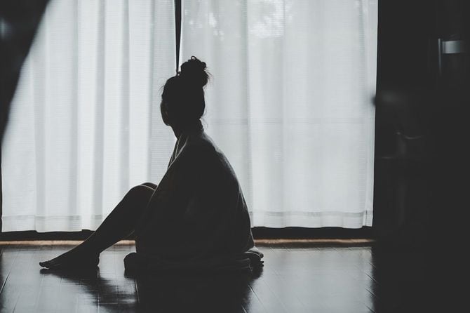 薄暗い部屋の床に座っている女性