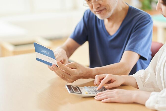 夫が通帳を確認し、妻が電卓を使用している