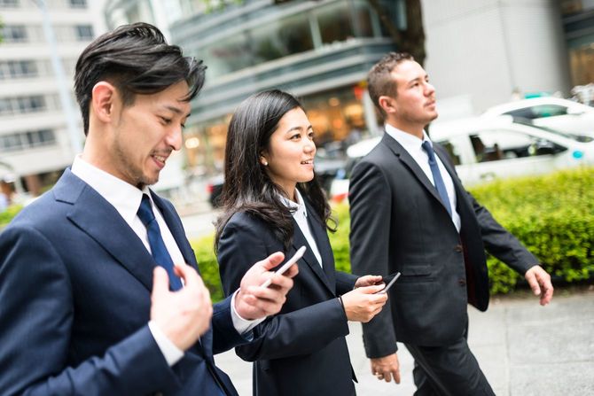 歩道を歩く3人の若いビジネスパーソン
