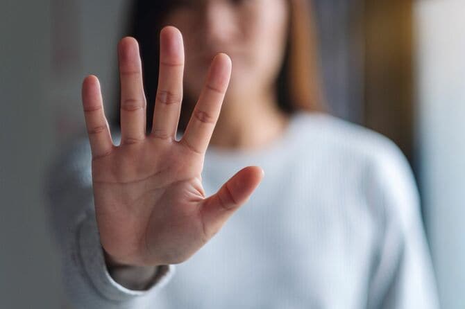 手を伸ばし、止まる手のサインを見せる女性