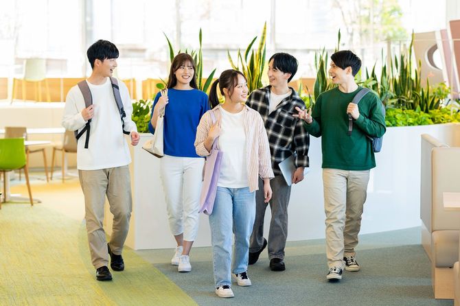 キャンパス内を笑顔で話しながら歩く大学生のグループ