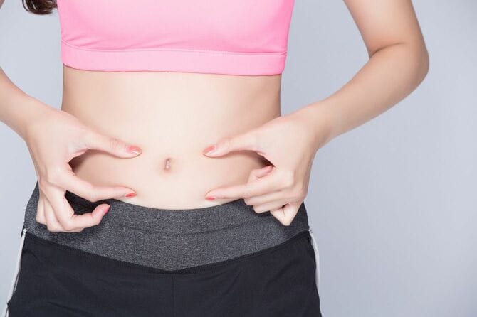 お腹をつまむ女性