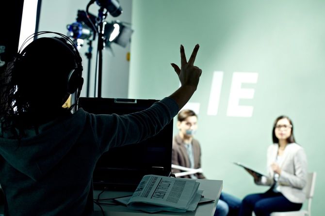 放送開始のタイミングをハンドサインで送るカメラマン