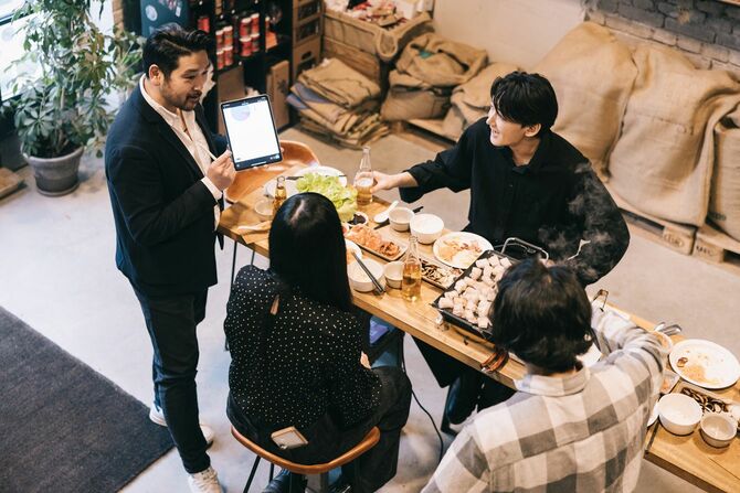 おしゃれなスペースに集い食べながら仕事の話をしている若い実業家たち