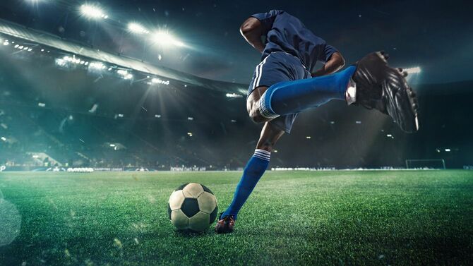 スタジアムでライトに照らされながらプレーするサッカー選手