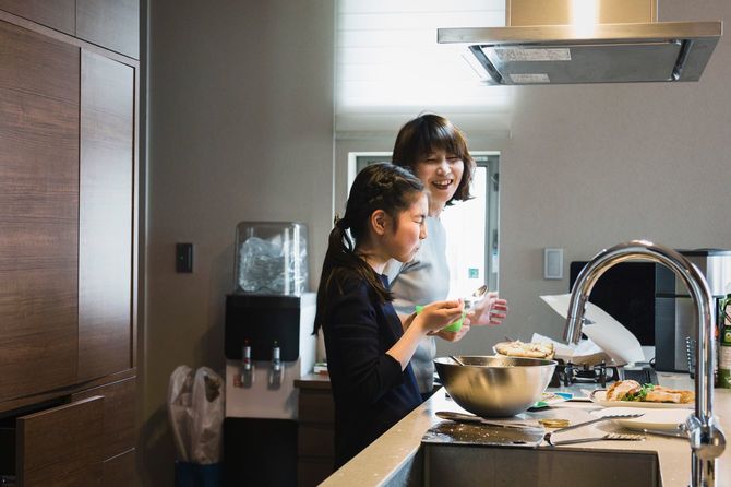 母親と一緒にキッチンに立って調理する少女