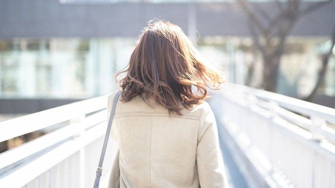 歩道橋を歩くビジネスウーマンの後ろ姿