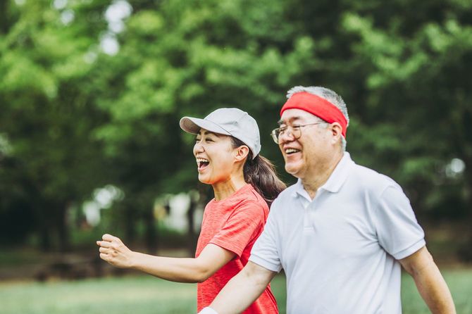 高齢者と若い女性が公園内をウオーキング