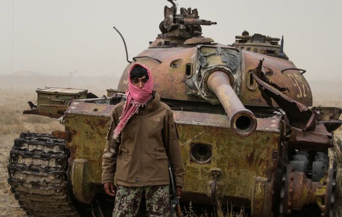 アフガニスタン・ガルデスにて、古い戦車の前に立つ男性