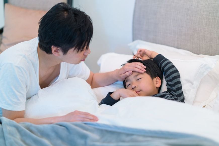 父親が自宅の寝室で病気の男の子の世話