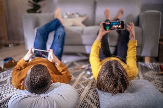 家で携帯電話でゲームをする男の子と女の子