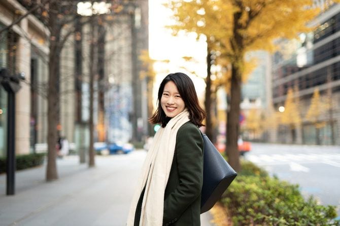 秋の歩道で、笑顔で振り返る女性