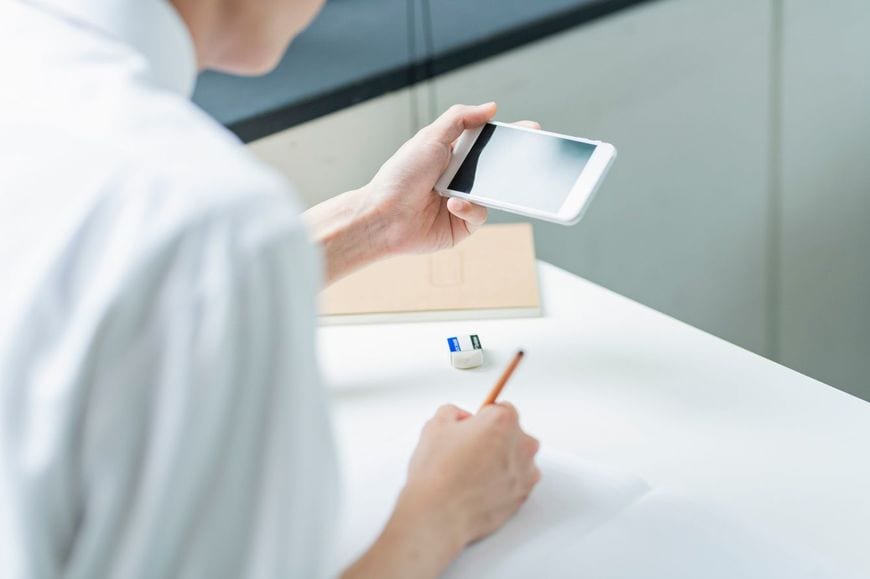 スマホを片手にメモを取っている男子生徒