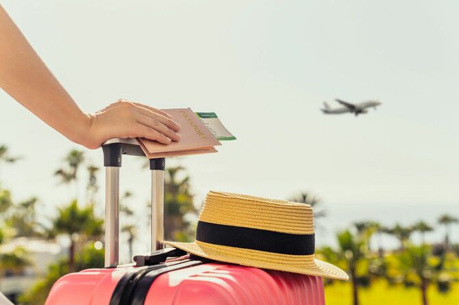 ピンクのスーツケースとパスポートを持つ女性