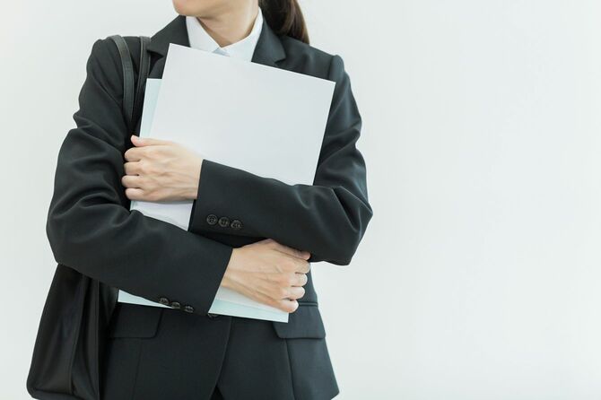 書類を抱えて所在なく立っている新入社員