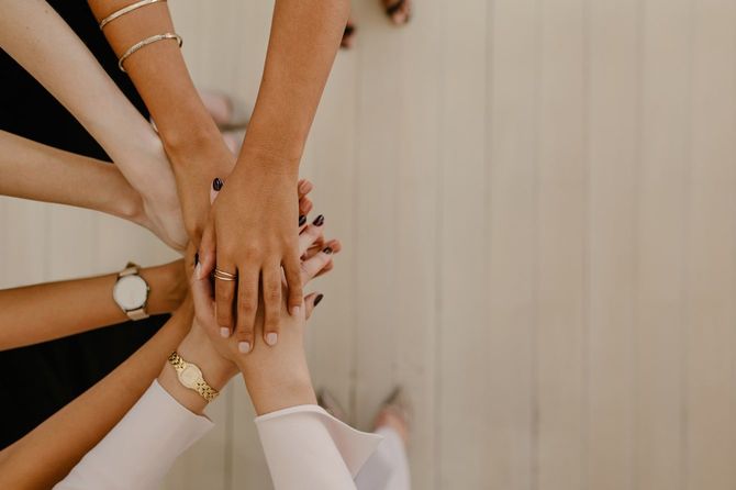 円陣を組んで手を重ね合わせる女性チーム