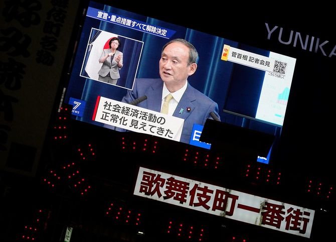 菅義偉首相の記者会見を映す大型ビジョン。政府は、新型コロナウイルス対策で半年近くに及んだ緊急事態宣言を30日の期限をもって全面解除すると発表した
